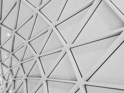 An intricate ceiling design featuring modern geometric patterns and steel structures in a low angle shot.